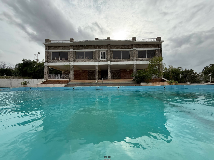 Outdoor swimming pool surrounded by palm trees at Kanthi Resorts, resort with swimming pool in Badami